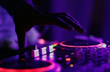 selective focus silhouette photography of man playing red-lighted DJ terminal