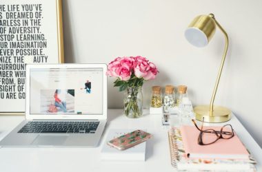 MacBook Air beside gold-colored study lamp and spiral books