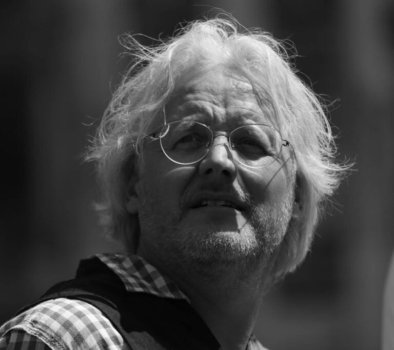 Black and white portrait of an elderly man wearing glasses in Brussels.