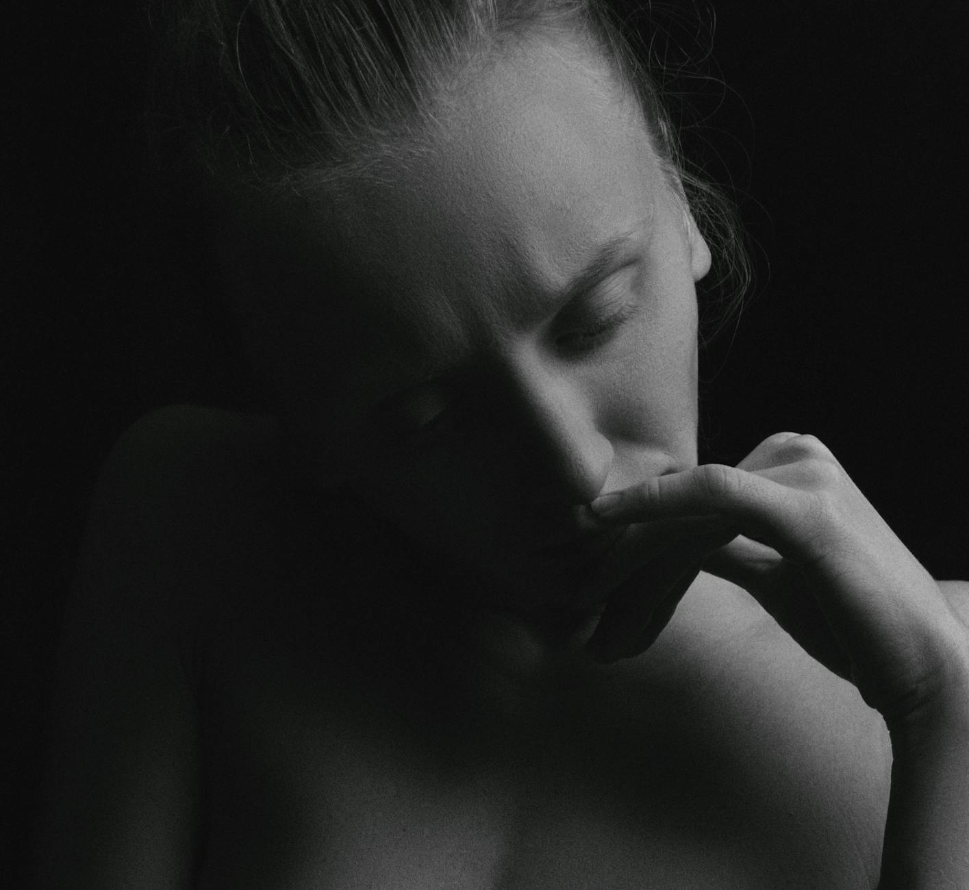 Emotive black and white portrait of a woman with contemplative expression, hand on chin.