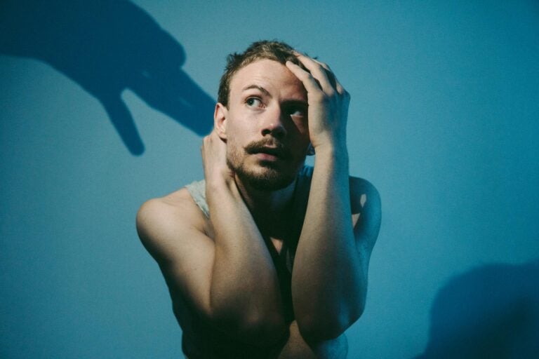 Artistic portrait of a man in blue lighting, contemplating with shadow play.