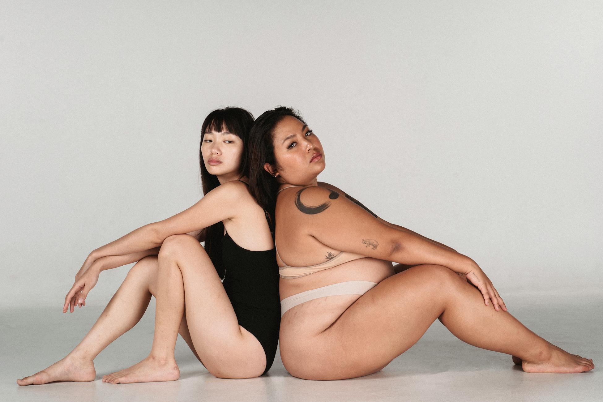 Two women back to back, celebrating individuality and body positivity.