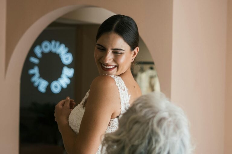 A smiling bride in a lace dress joyfully turns, celebrating her special day indoors.