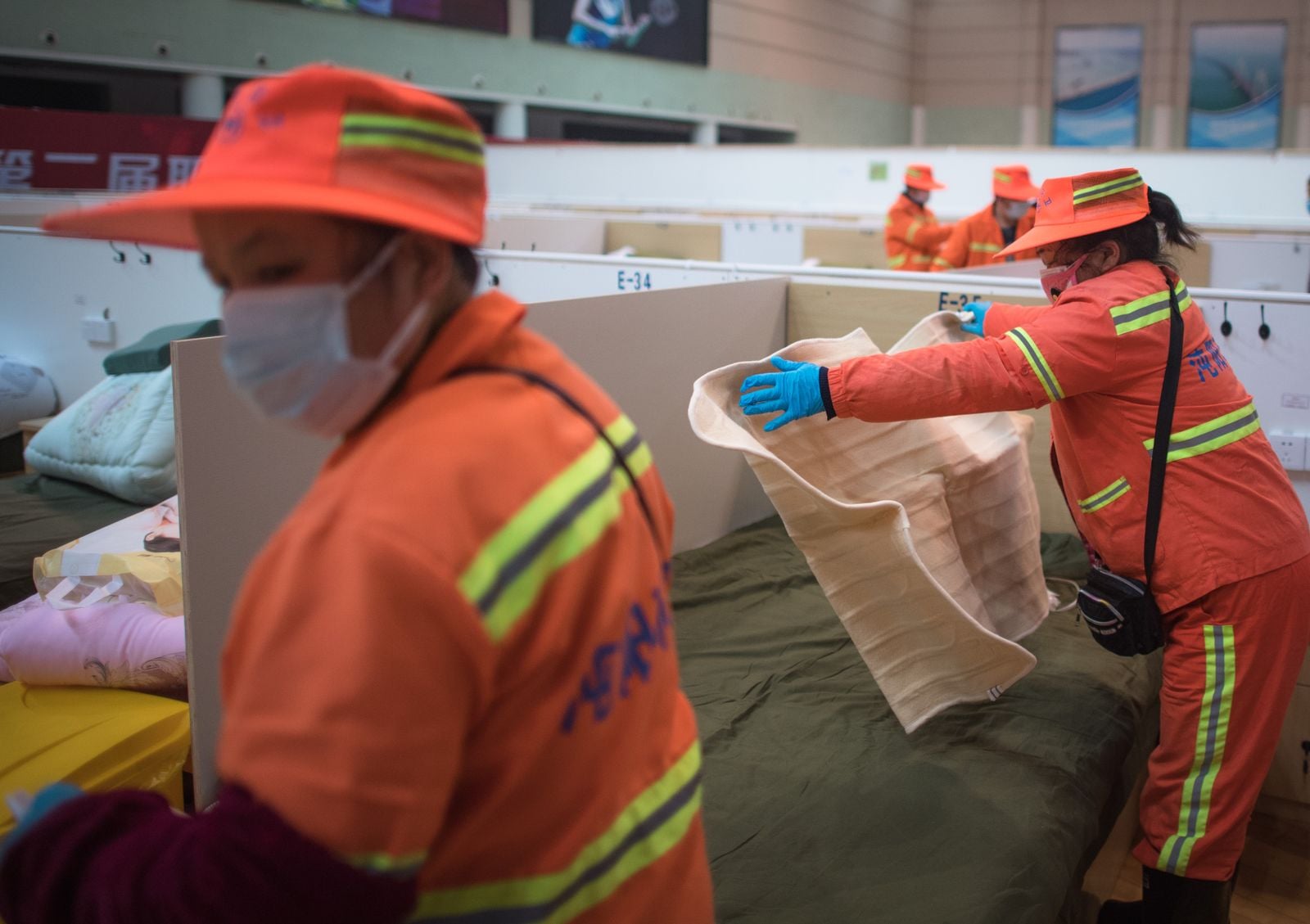 Paramedics setting up temporary beds in an indoor facility
