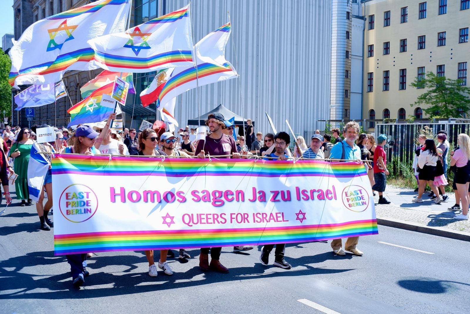 Participants carrying Queers for Israel flags and a banner at a Pride event in Berlin