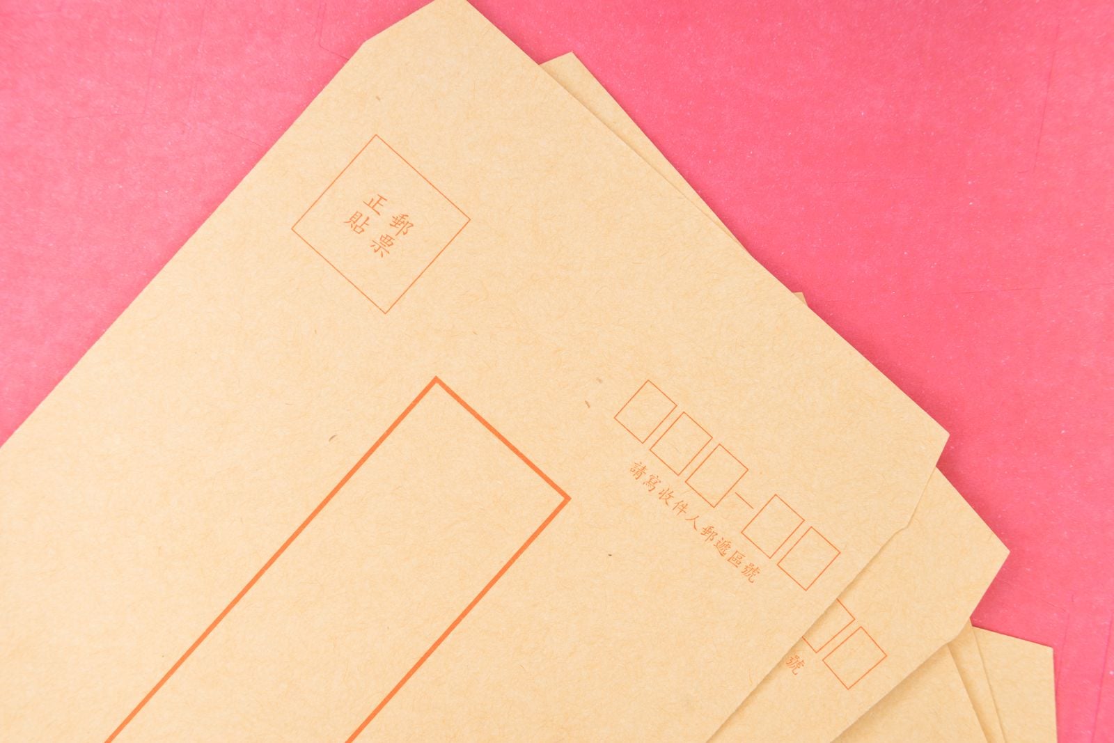 brown envelopes on a pink surface